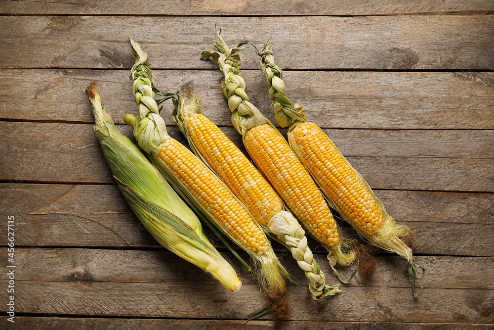 Fresh corn cobs on wooden background