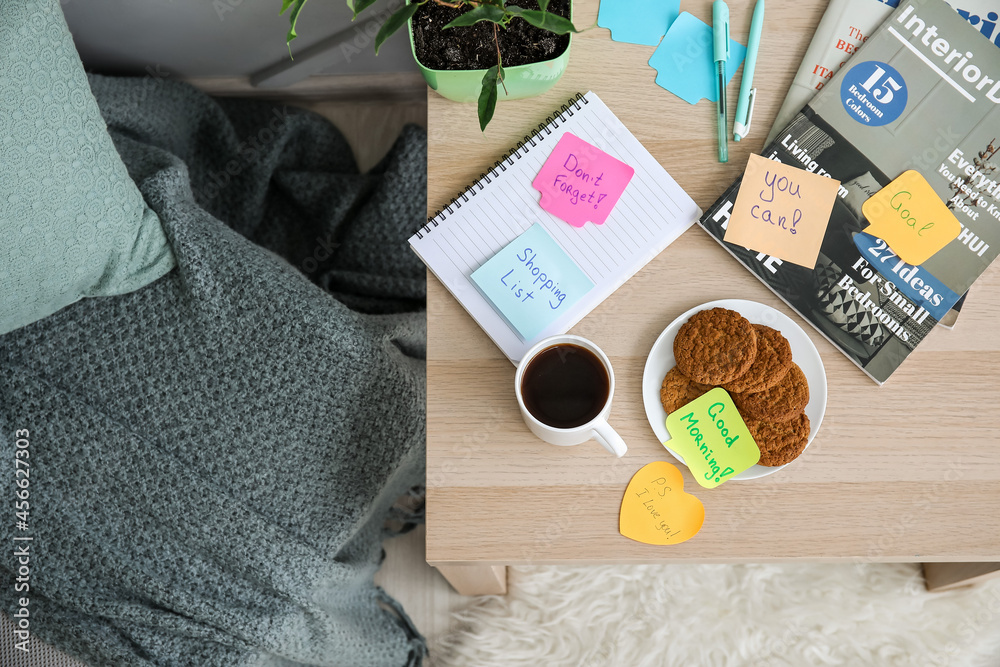 Cup of coffee, cookies and motivation sticky notes on table