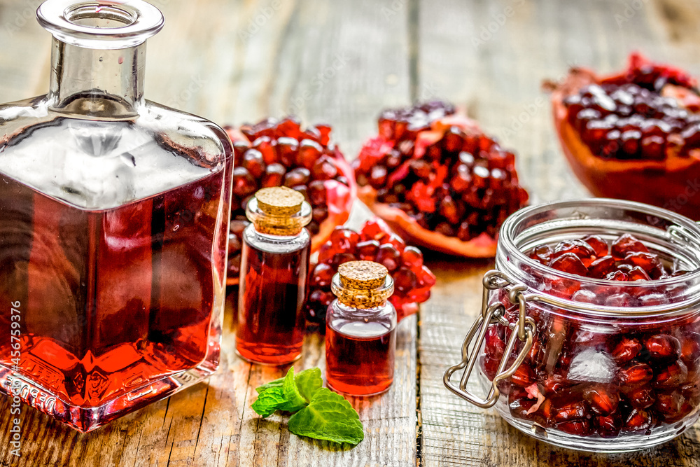 sliced pomegranate and extract in glass on wooden background