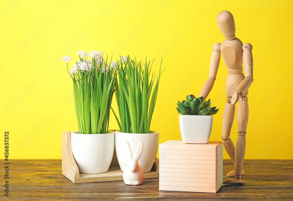 Wooden mannequin with plants on color background. Concept of gardening