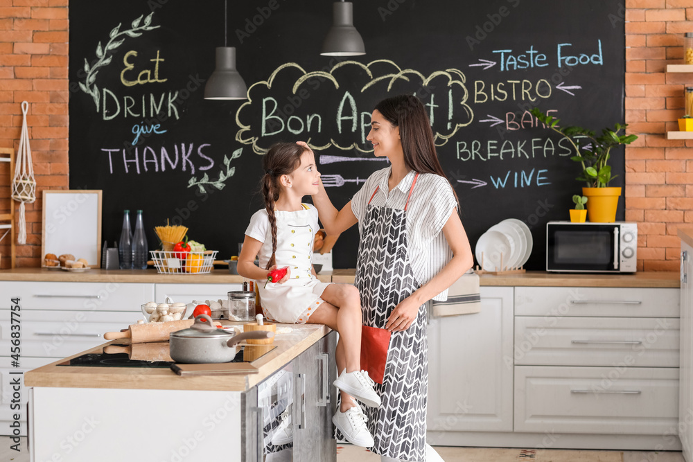 Young mother and daughter in kitchen at home