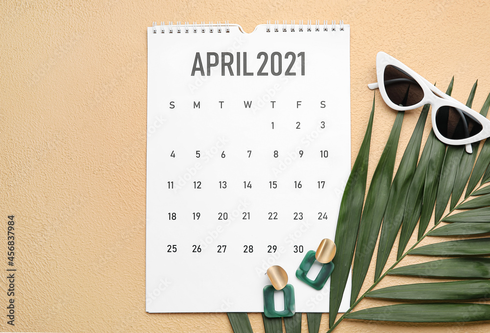 Calendar with female accessories and tropical leaf on color background