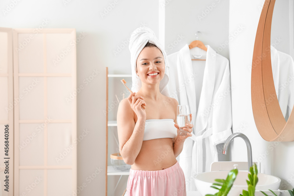 Young woman brushing teeth in bathroom