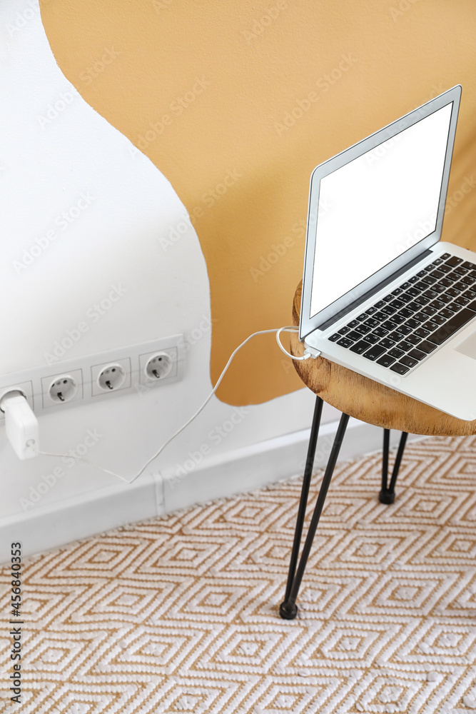 Table with charging laptop near color wall