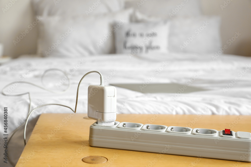 Extension cord with plug on table in bedroom