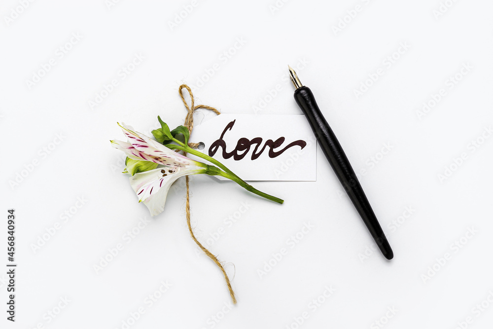 Paper with word LOVE, nib pen and flower on white background