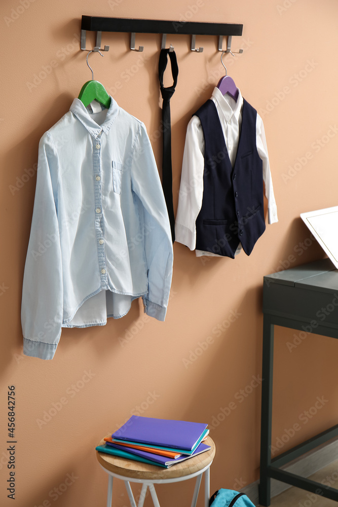 School uniform hanging on color wall