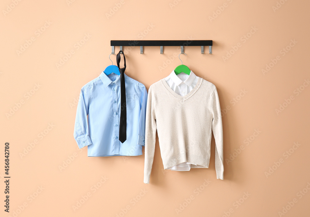 Stylish school uniform hanging on color wall