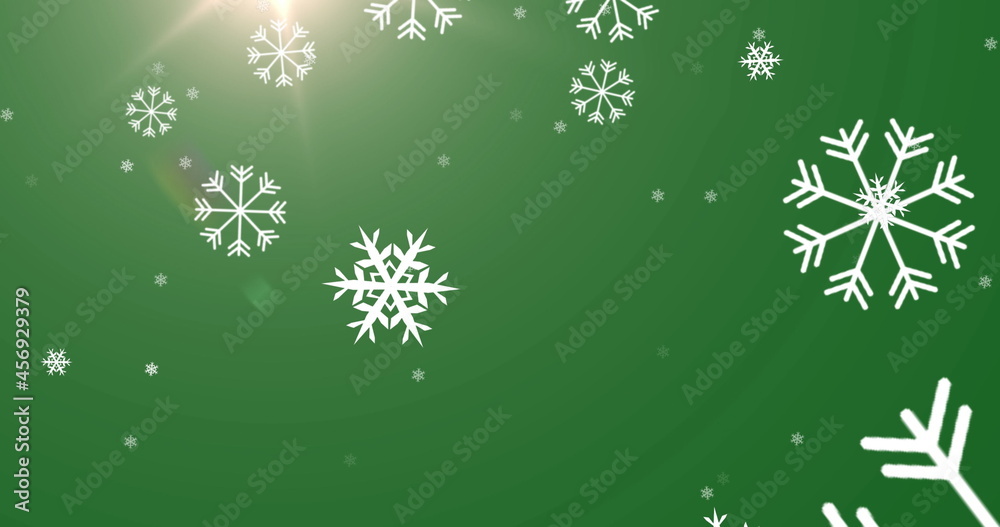 Digital image of snowflakes falling against bright spot of light on green background