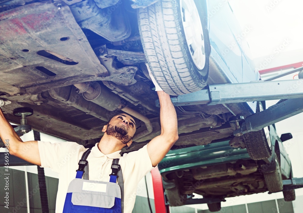 Technical inspection of the car. Car service in the workshop. A man under a car