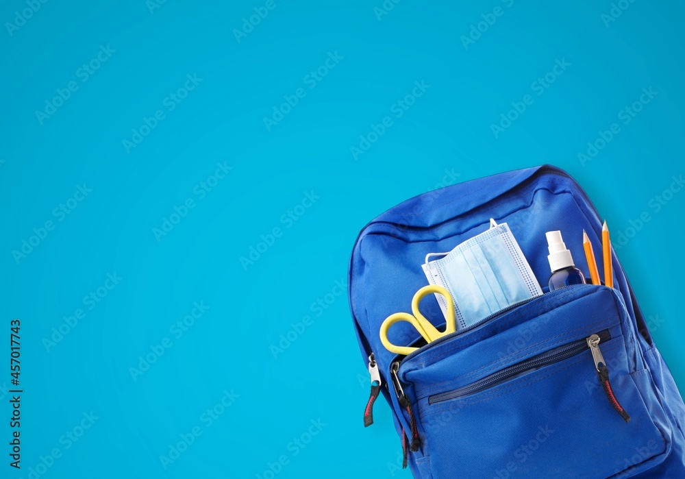 School backpack with different colorful stationery products on desk