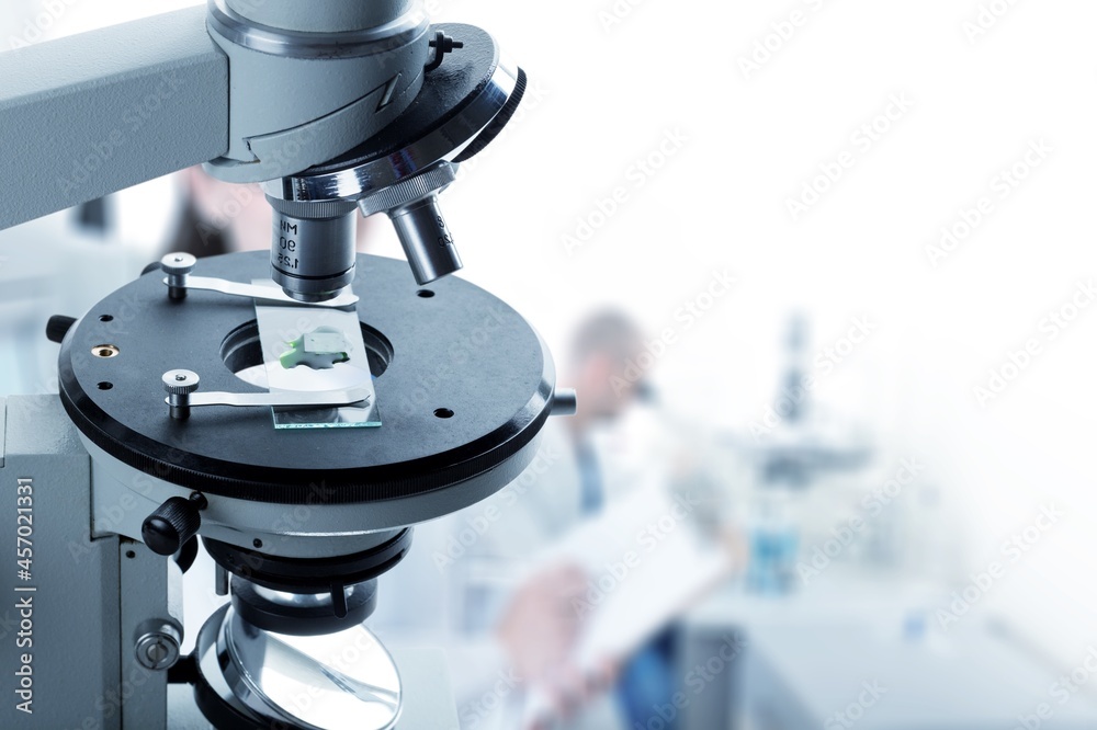 Electronics engineering scientist working with microscope looking at silicon micro chip.