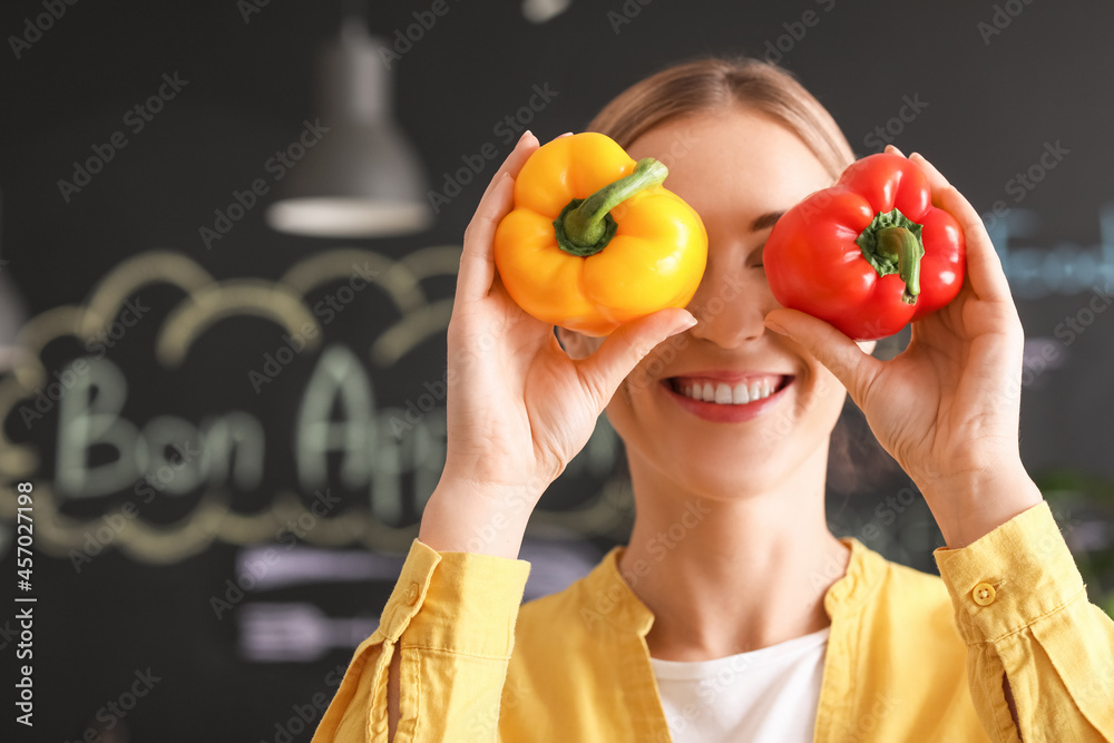 Happy housewife with bell peppers in kitchen at home