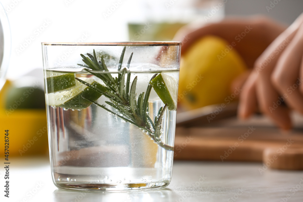 Glass of tasty lime cocktail with rosemary on table, closeup