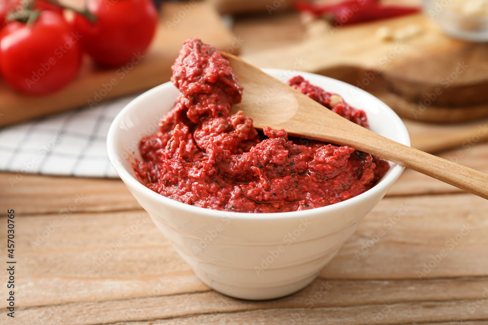 Bowl of tasty pesto sauce on wooden background