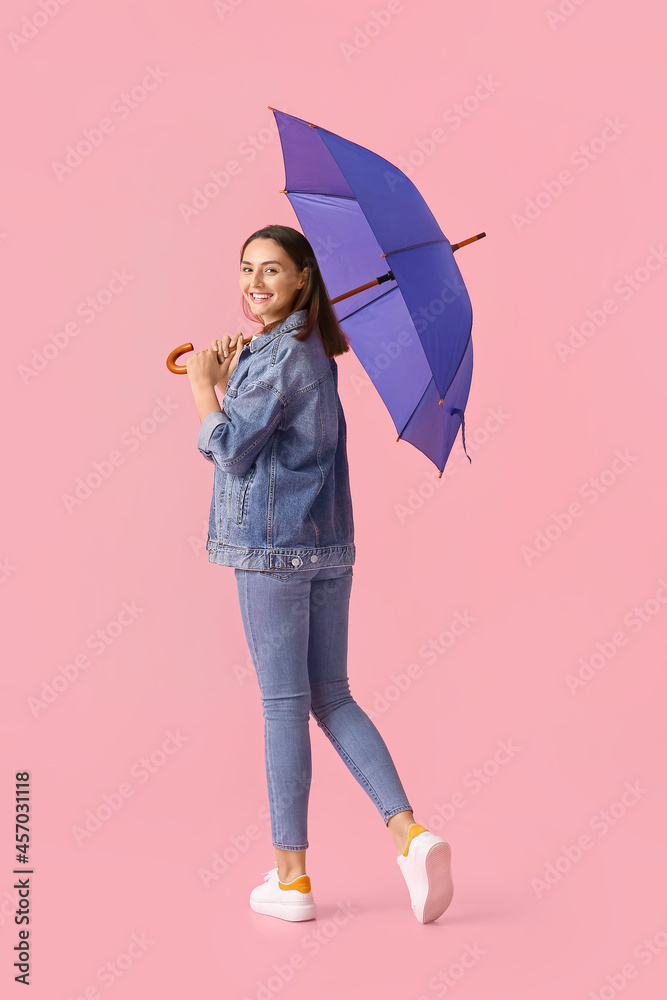 Beautiful young woman with umbrella on color background