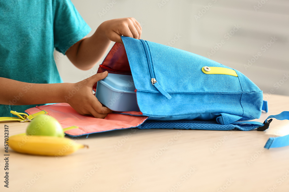 可爱的小男孩把学校的午餐放在袋子里