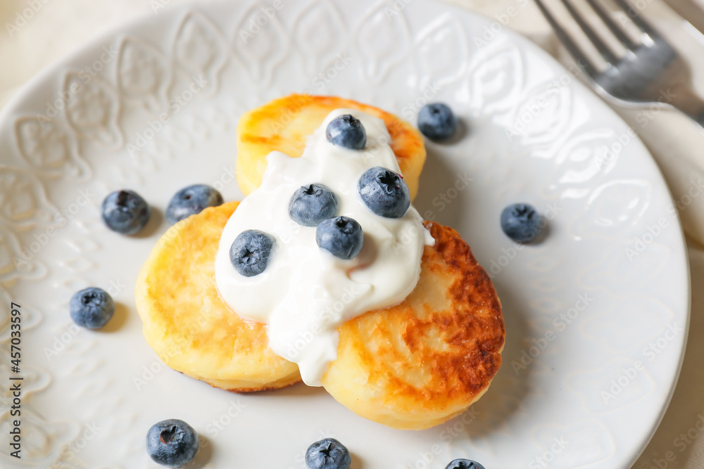 Plate with cottage cheese pancakes and blueberry on table, closeup