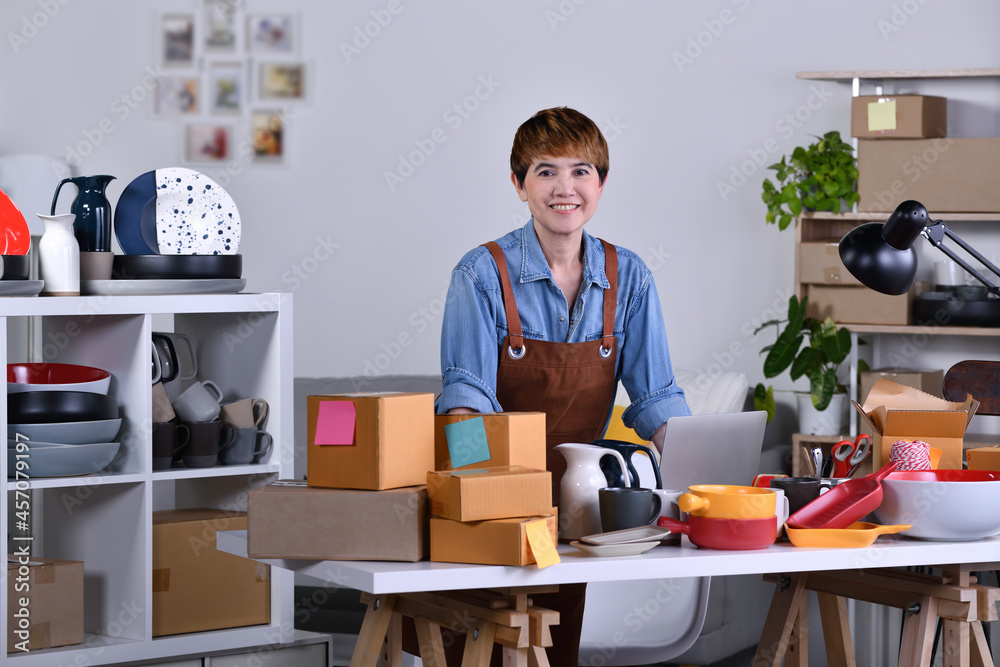 Mature Asian woman entrepreneur, Business owner standing and working at home office with her clay ce