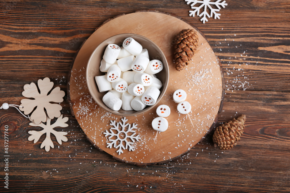 Bowl with snowmen made of soft marshmallows on wooden background