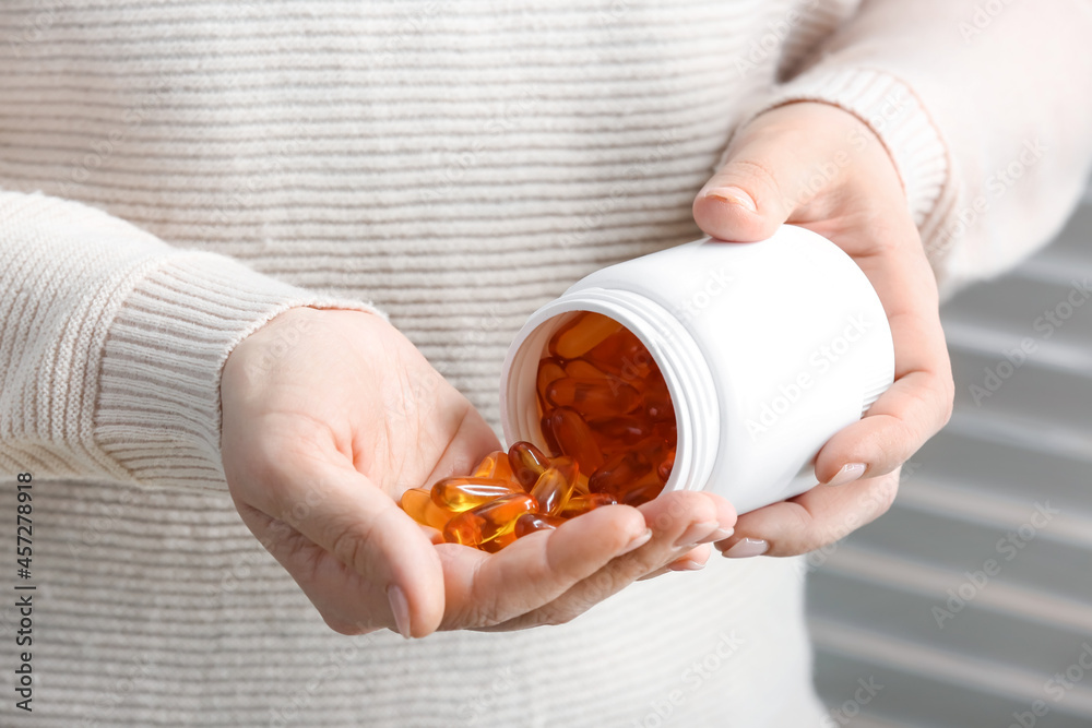 Woman taking fish oil pills, closeup