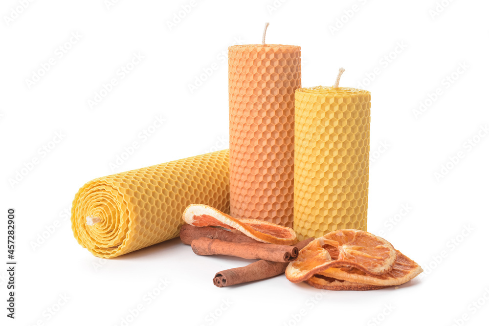 Composition with wax candles, cinnamon and dried orange on white background