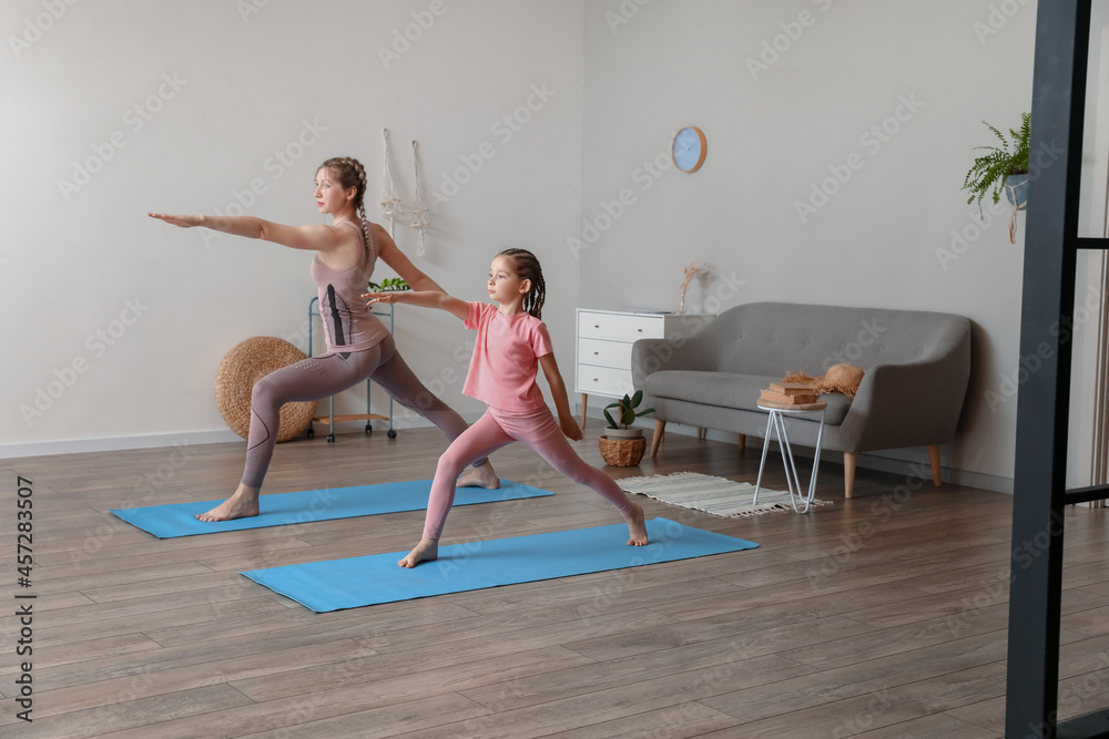 Little girl with her mother practicing yoga at home