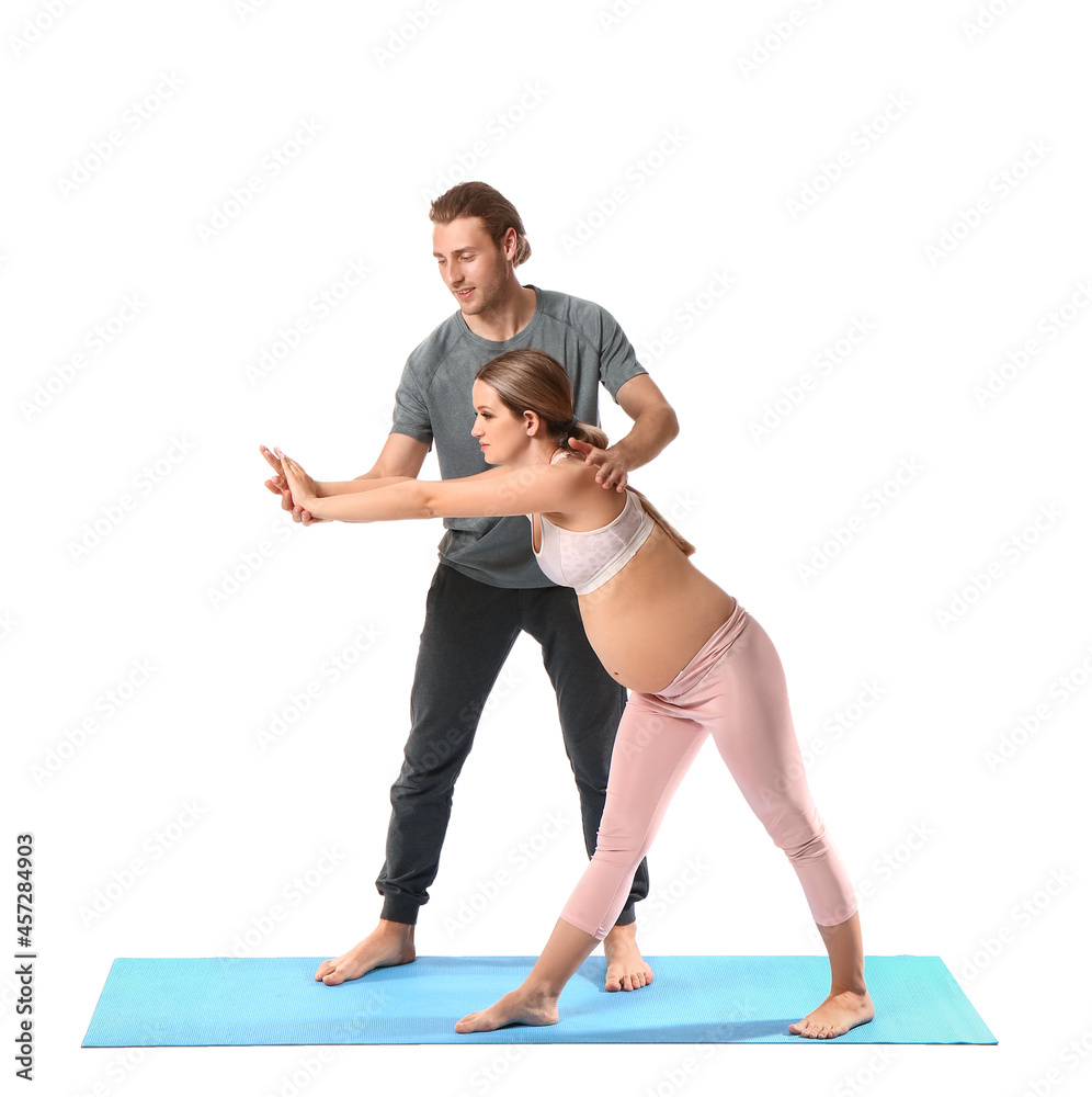 Young pregnant woman and her husband practicing yoga on white background