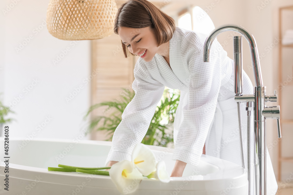 Young woman running bathtub with warm water at home