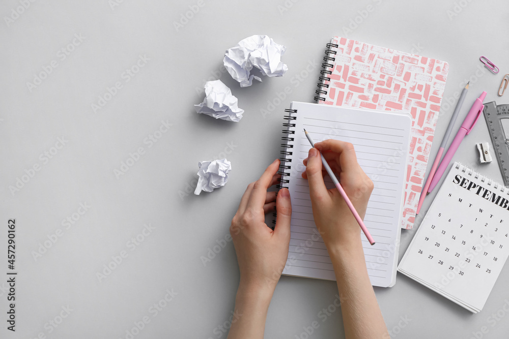 Woman writing in notebook on grey background