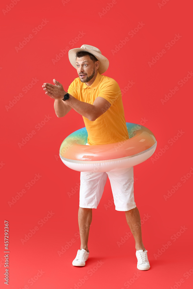 Young man with inflatable ring on color background