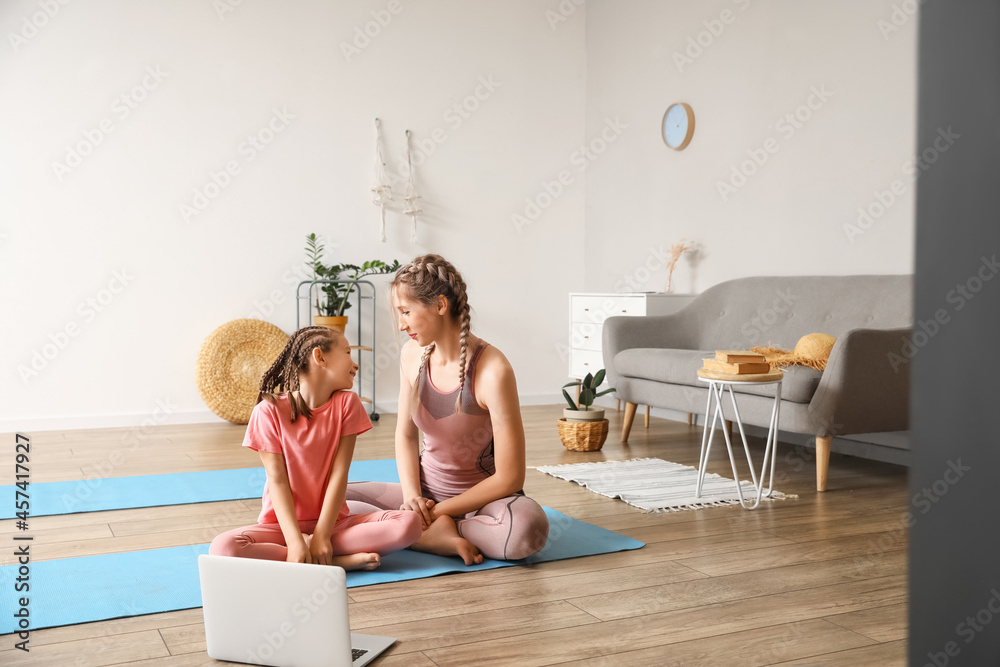 Little girl with her mother practicing yoga at home