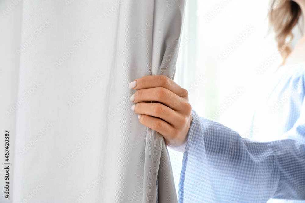 Woman opening light curtains in modern room, closeup