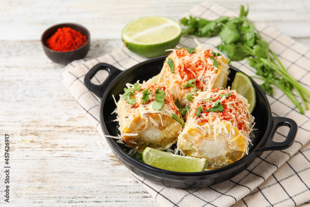 Frying pan with tasty Elote Mexican Street Corn on white wooden background