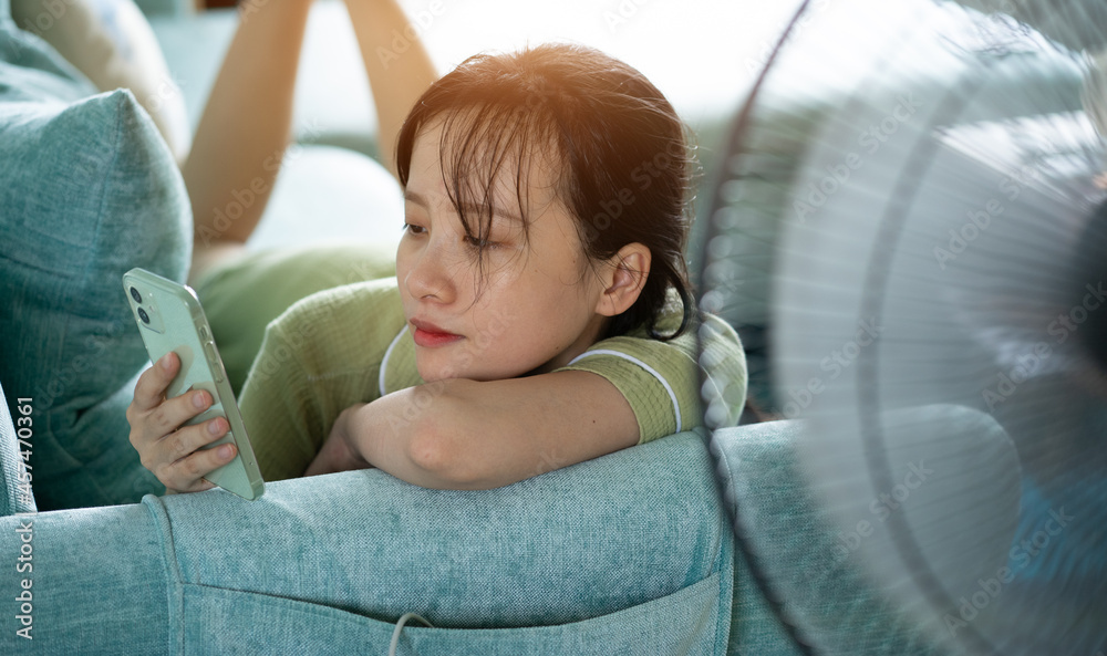 Asian girl lying on sofa and using phone