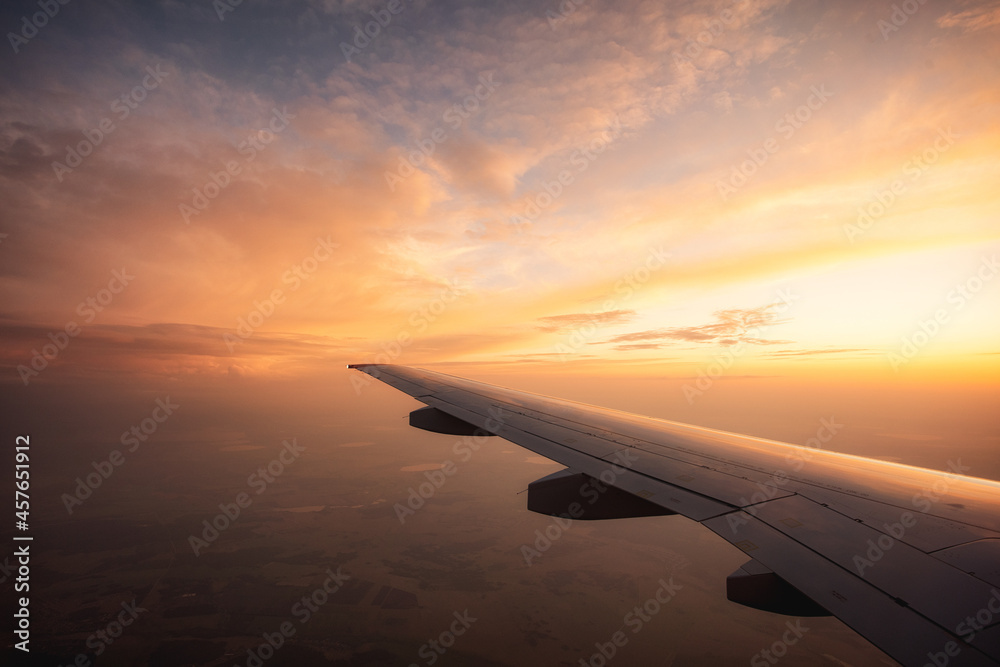 Flying high over endless fields Airplane wing and sunset. Long flight abroad. Tourism and travel.