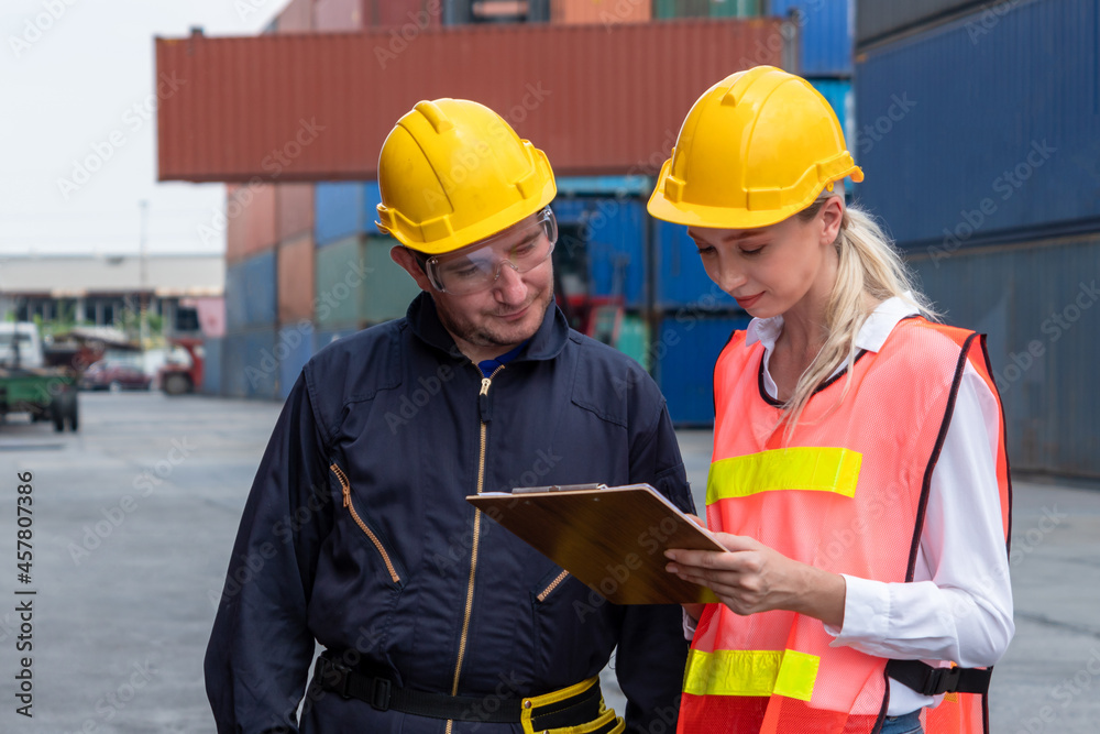 Industrial worker works with co-worker at overseas shipping container yard . Logistics supply chain 