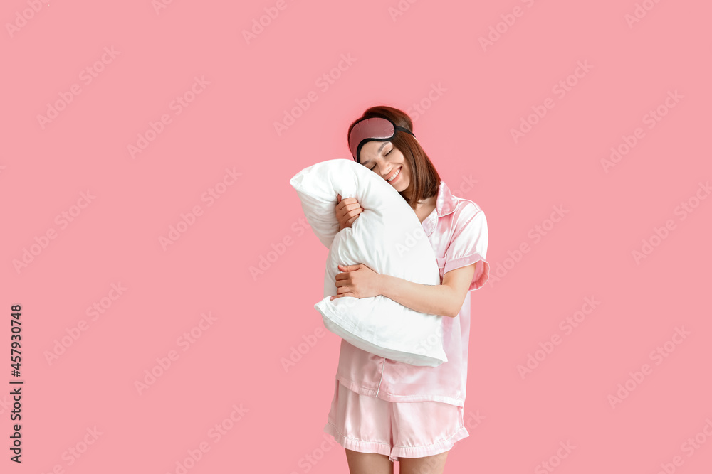 Young woman hugging pillow on color background