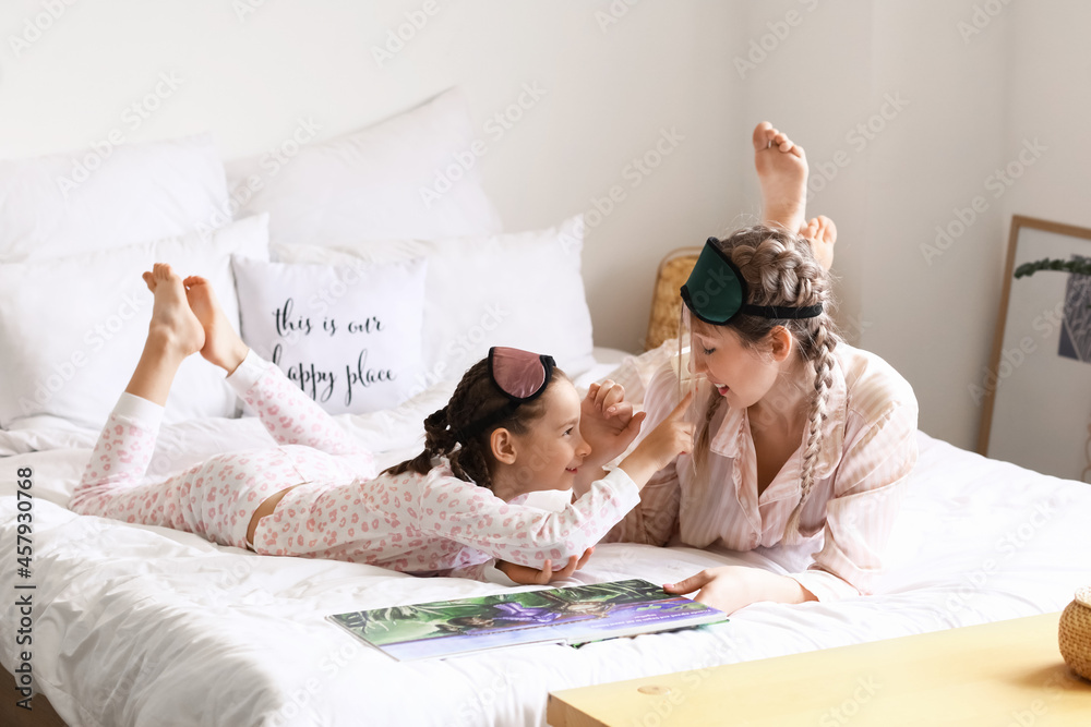 Little girl with her mother reading fairy-tale in bedroom