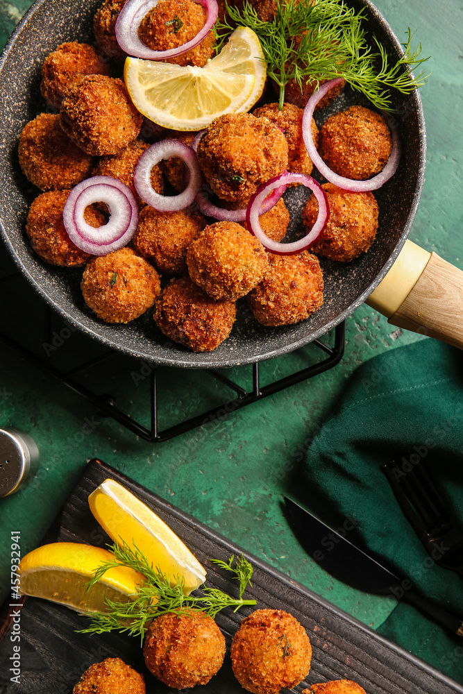 Frying pan with tasty cod cutlets on color background