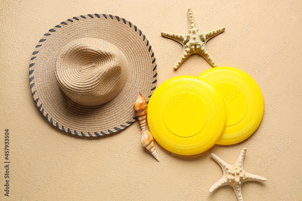 Frisbee disks, hat, starfishes and seashells on color background