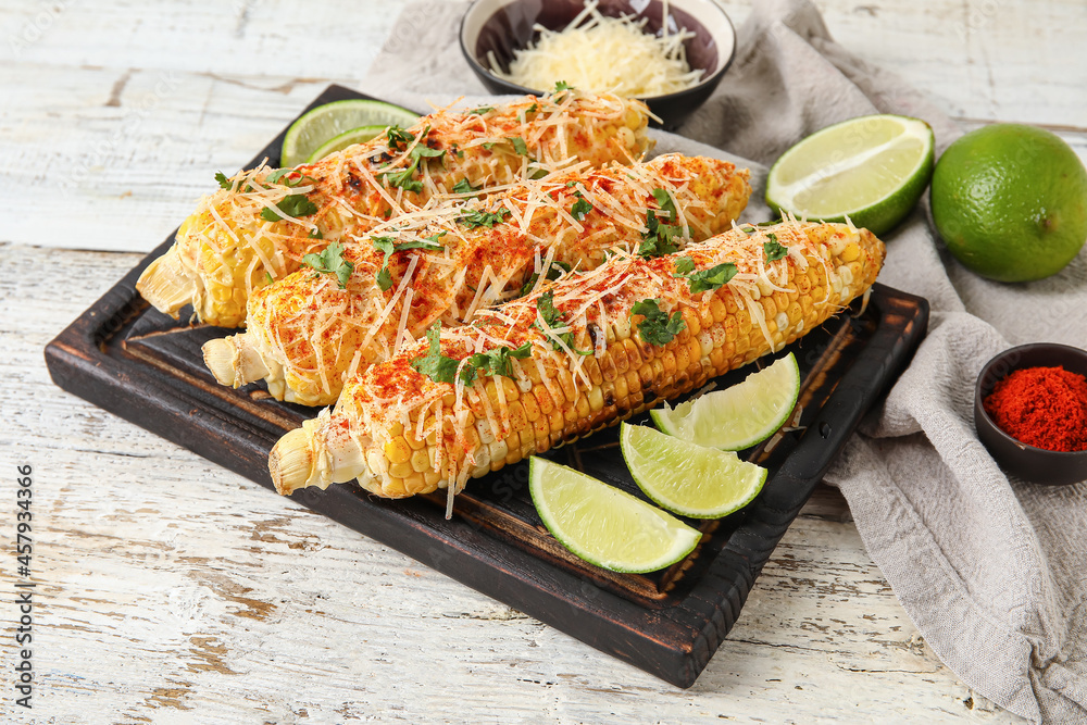 Board with tasty Elote Mexican Street Corn on white wooden background