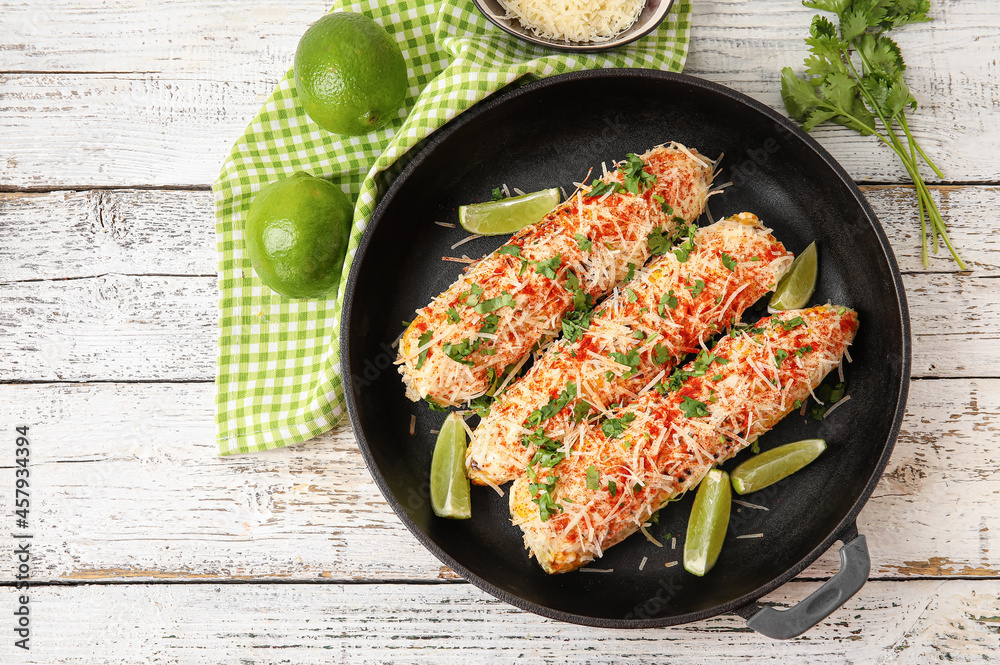 Frying pan with tasty Elote Mexican Street Corn on white wooden background