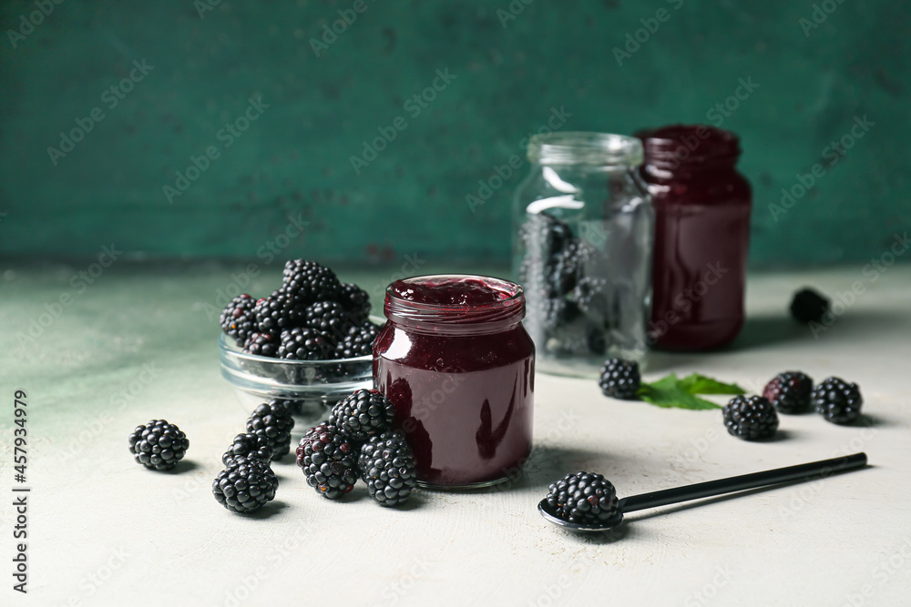 Composition with jar of tasty blackberry jam and berries on table