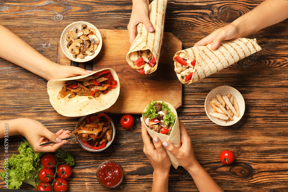 Women eating tasty Fajitas on wooden background