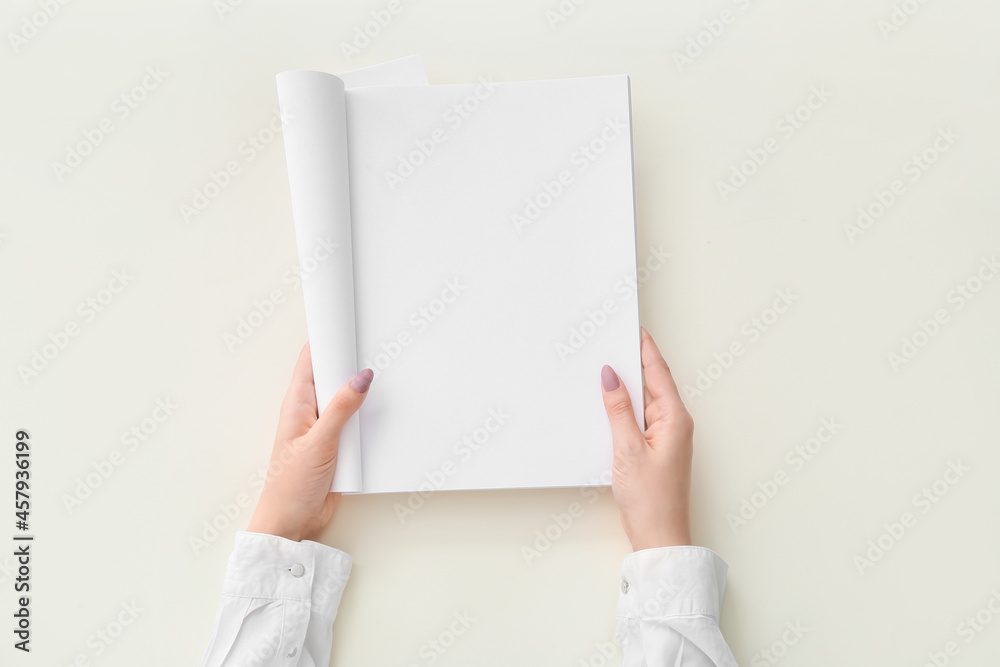 Female hands with blank magazine on light background