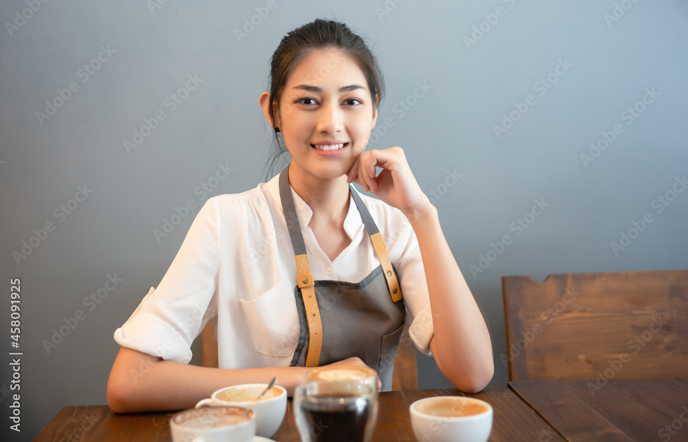 职业咖啡师亚洲女性或小企业女老板坐在桌子上微笑的肖像