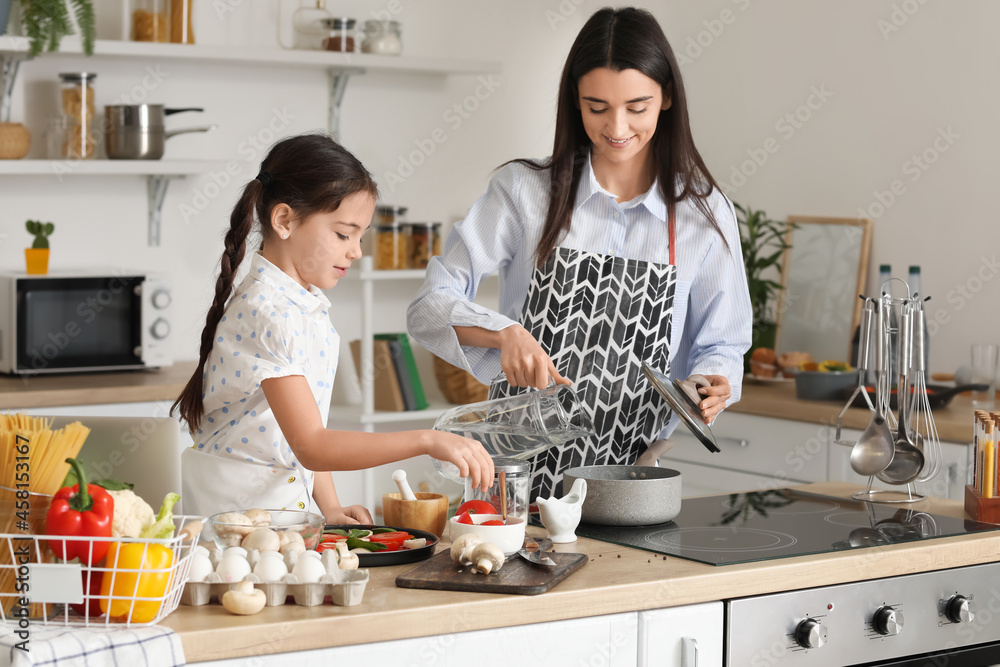 年轻的母亲和女儿在家的厨房里一起做饭