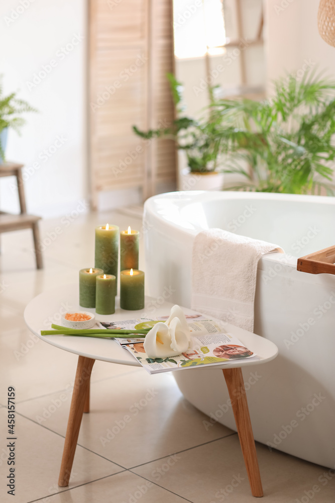 Table with flowers, magazine and candles in bathroom