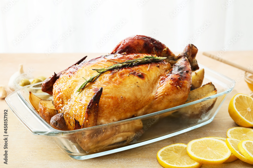 Baking dish with tasty chicken and lemon on table, closeup